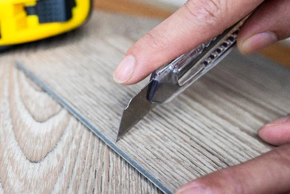 Person schneidet Vinylboden mit Teppichmesser